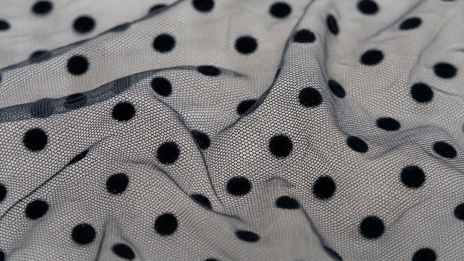 Tule flocado com bolinhas pretas aplicadas sobre a malha transparente