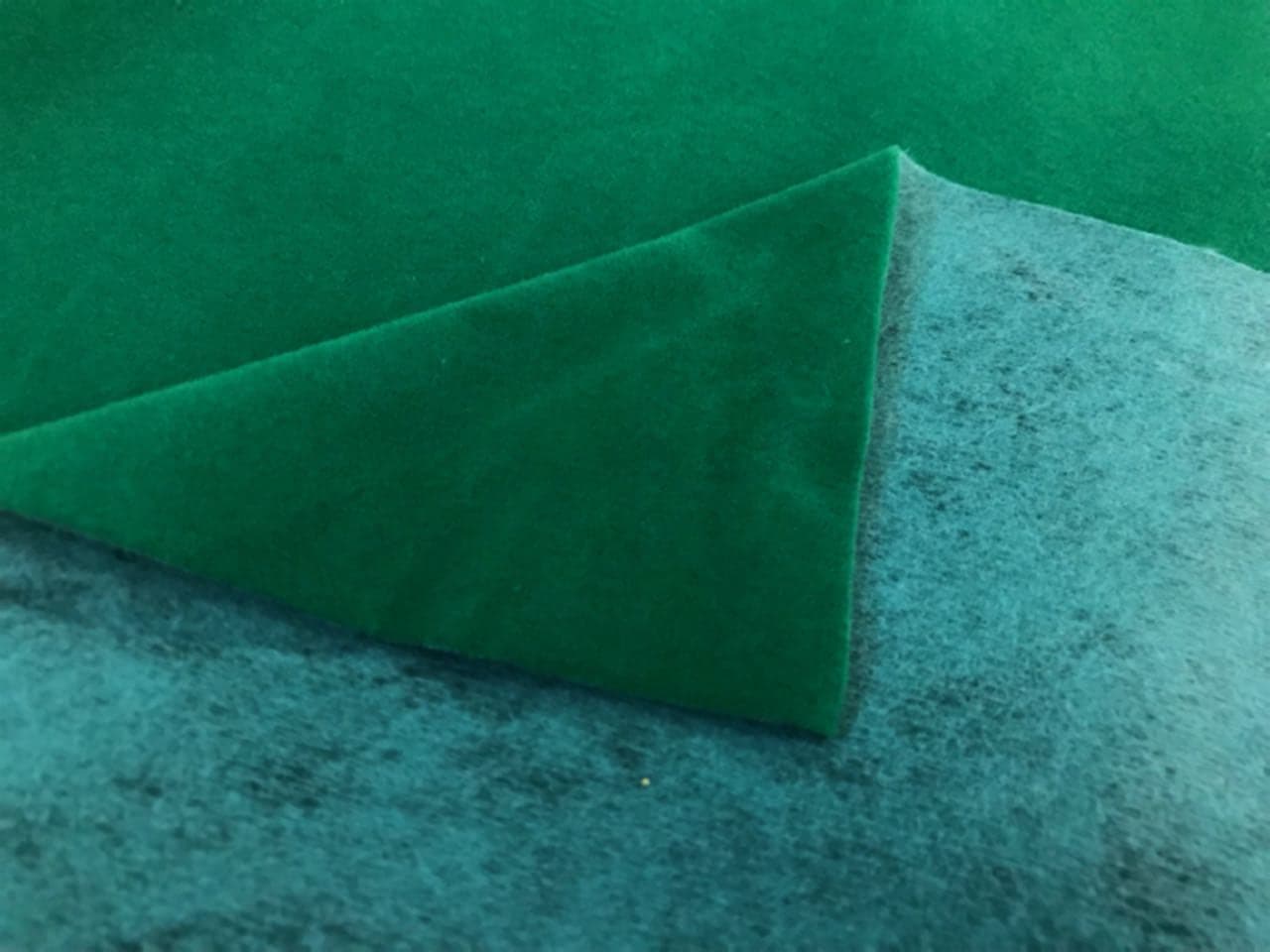 Veludo verde com a ponta dobrada, mostrando o verso de manta tingida na mesma cor