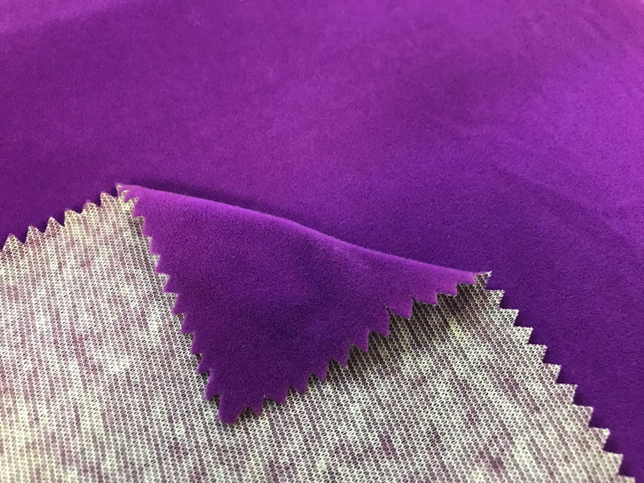 Veludo roxo com borda serrilhada dobrada, mostrando o verso de malha